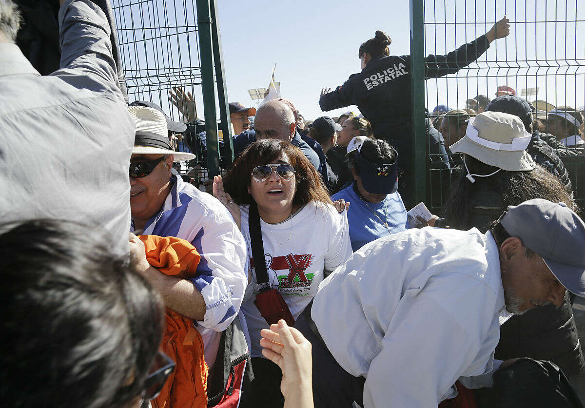People push forward as they enter the area where Pope Francis will celebrate an outdoor Mass, in Ciudad Juarez, Mexico, Wednesday, Feb. 17, 2016. Just before the start of his Mass in a large field in Juarez, Francis is expected to make a short walk to the border fence along the Rio Grande. (AP Photo/Gregory Bull)