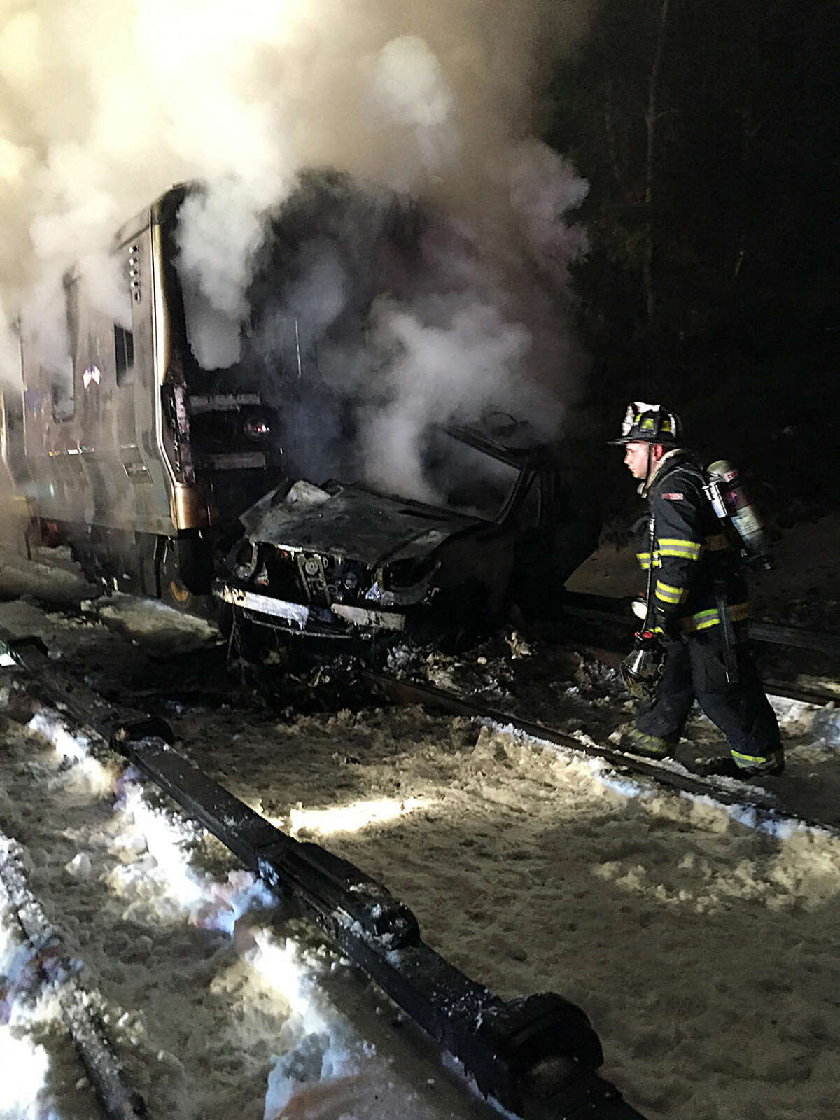 A firefighter walks past the burning wreckage of a Metro-North Railroad passenger train and a vehicle in Valhalla, N.Y., Tuesday, Feb. 3, 2015. Metro-North Railroad spokesman Aaron Donovan says the train struck a vehicle at a railroad crossing about 20 miles north of New York City. (AP Photo/The Journal News, Albert Conte)