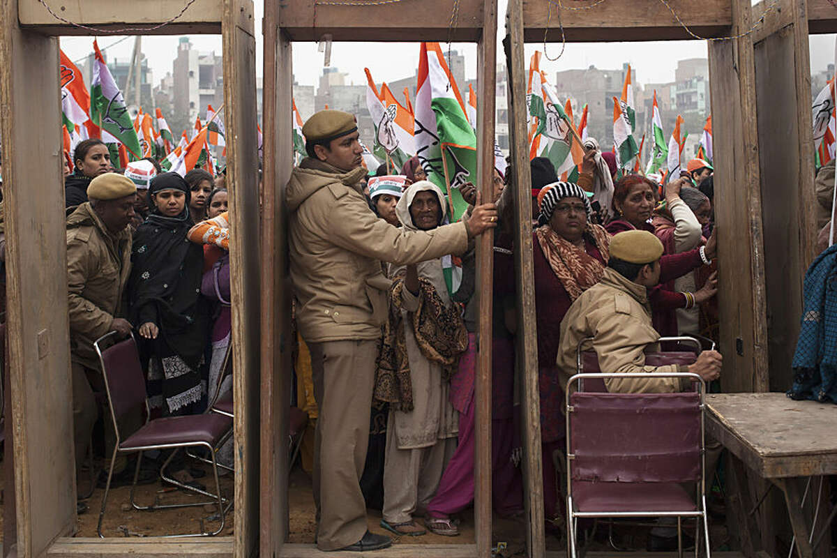 India's opposition Congress party supporters wait to enter the rally ground as policemen wait beside security gates during an election campaign rally ahead of Delhi state election in New Delhi, India, Wednesday, Feb. 4, 2015. Delhi goes to the polls on Feb. 7. (AP Photo/Tsering Topgyal)