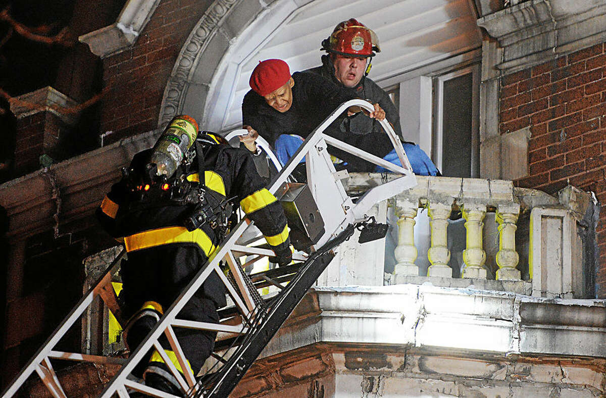 Firefighters rescue a person during a fire at the Norris Apartments building, Wednesday, Feb. 4, 2015, in Norristown, Pa. One resident died and at least three people were injured in the overnight fire that collapsed part of the 140-year-old apartment building. (AP Photo/The Times Herald, Tom Kelly IV)
