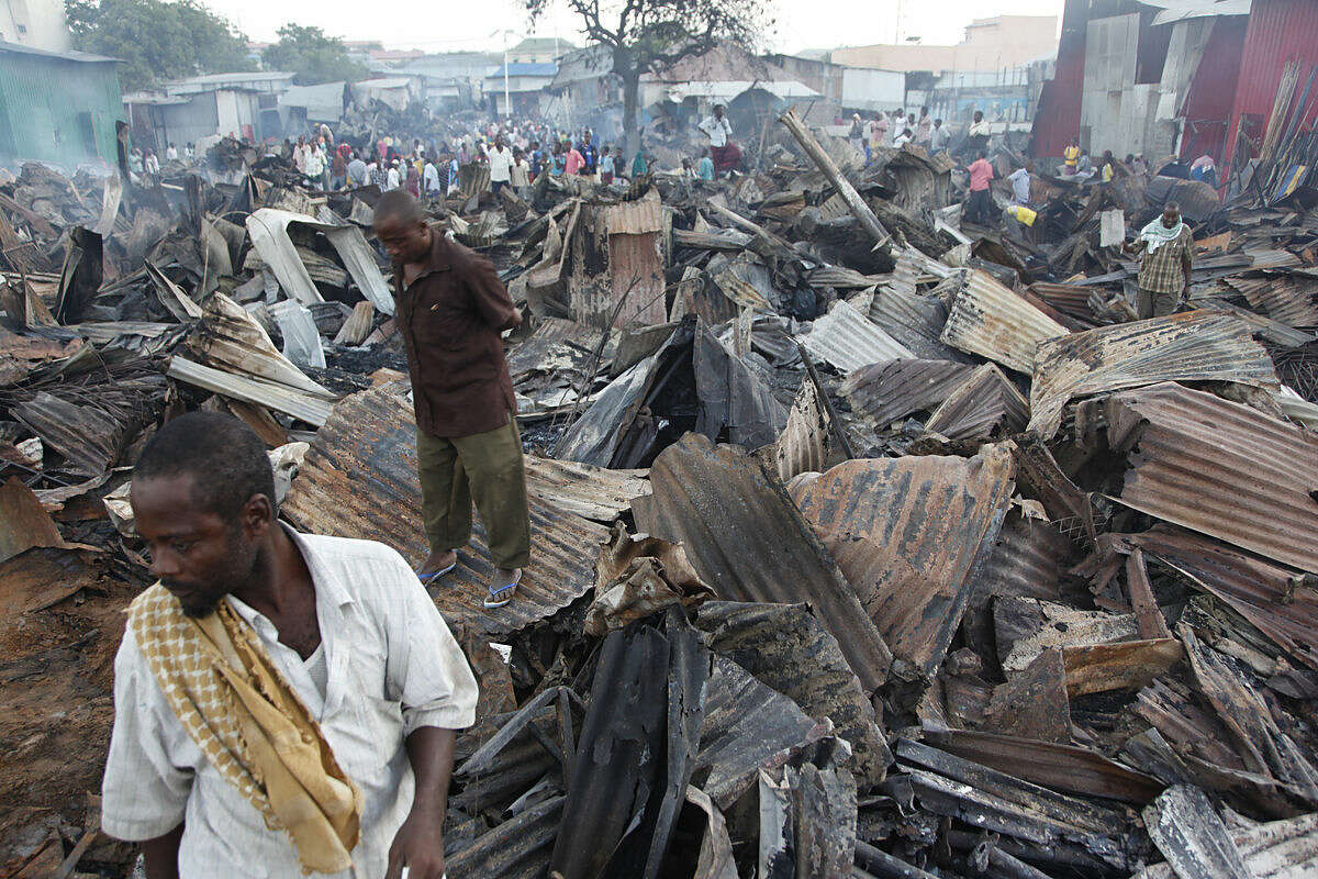 Somali shopkeepers stand on destroyed and burnt iron sheets after a fire gutted hundreds of shops and restaurants in the Wadajir district, in the capital Mogadishu, Somalia Tuesday, Feb. 16, 2016. (AP Photo/Farah Abdi Warsameh)