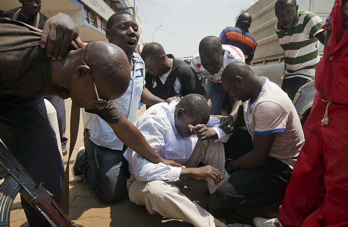 Leading opposition leader and presidential candidate Kizza Besigye, center, is surrounded by his bodyguards after being overcome by tear gas fired at him and his supporters by riot police, when they attempted to walk along a street in downtown Kampala, Uganda Monday, Feb. 15, 2016. Ugandan riot police arrested Besigye after tear-gassing him and his supporters when they tried to go from one election rally to another. (AP Photo/Ben Curtis)