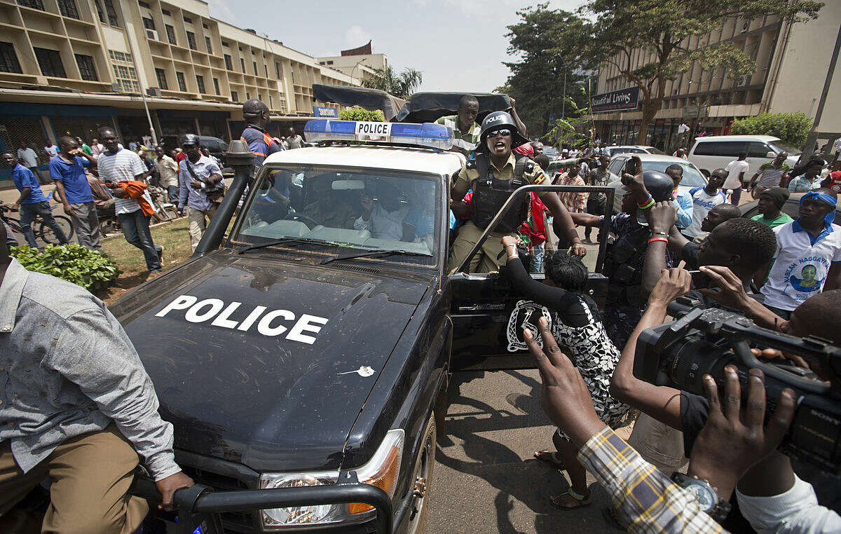 Leading opposition leader and presidential candidate Kizza Besigye, center, flashes the victory sign from the front seat of a police truck after being arrested by riot police when he attempted to walk with his supporters along a street in downtown Kampala, Uganda Monday, Feb. 15, 2016. Ugandan riot police arrested Besigye after tear-gassing him and his supporters when they tried to go from one election rally to another. (AP Photo/Ben Curtis)