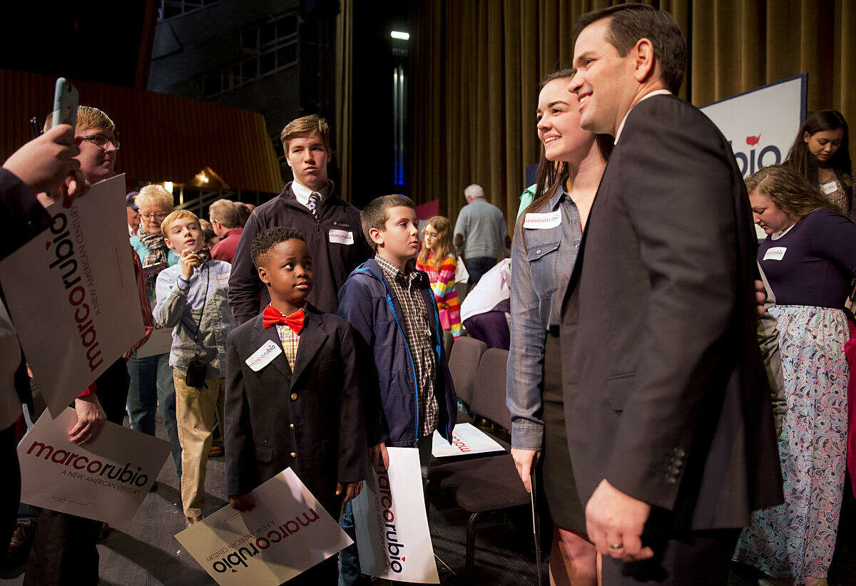 Tyler Merritts, 8, of Florence, S.C., left in red bow tie, watches as Republican presidential candidate Sen. Marco Rubio, R-Fla., takes pictures with supporter during a town hall meeting at Francis Marion University in Florence, S.C., Monday Feb. 15, 2016. Merritts' mother was in the audience and says that while she is still undecided that her son is definitely a Rubio fan. (AP Photo/Jacquelyn Martin)