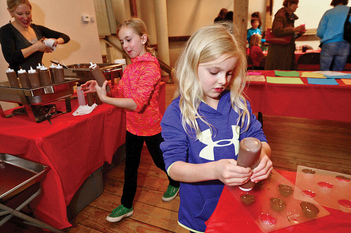 Hour photo / Erik Trautmann Bella and Ava Albers make chocolates during the Wilton Historical Society annual Valentine Chocolate-Making Workshop for kids in grades kindergarten through 8 Thursday. Program participants also made Valentines cards box to put the chocolates in. The one-hour session made use of an extensive collection of small, charming chocolate mold featuring hearts, a multitude of animals, and stars.