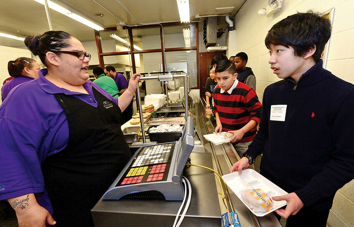 Hour photo / Erik Trautmann Whitson's Culinary Group food worker Erica Jimenez assists japanese student Hiroki Yamakawa as Ponus Ridge Middle School hosts nine students from the Greenwich Japanese School Thursday. Ponus Ridge Japanese teacher, Mrs. Misae Pergolizzi, has established a relationship with the school to help foster student interest in their Japanese language program.