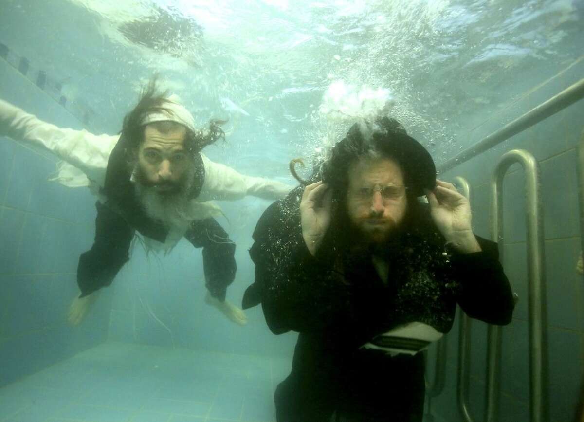 This undated photo provided by Channel 8 and Go2Films shows Ori Gruder, left, and rabbi Yisrael Aharon Itzkovitz swimming in their clothes in a ritual bath, which is created for publicity purpose for "Sacred Sperm," a film Gruder directed. The movie has been screened at festivals in Israel, London and California and continues in the coming weeks to other U.S. locations, including Atlanta on Feb. 15, 2015. Gruder created "Sacred Sperm," an hour-long documentary in which he tries to tackle the hard questions he can expect from his son. (AP Photo/Gliad Kavalerchik)