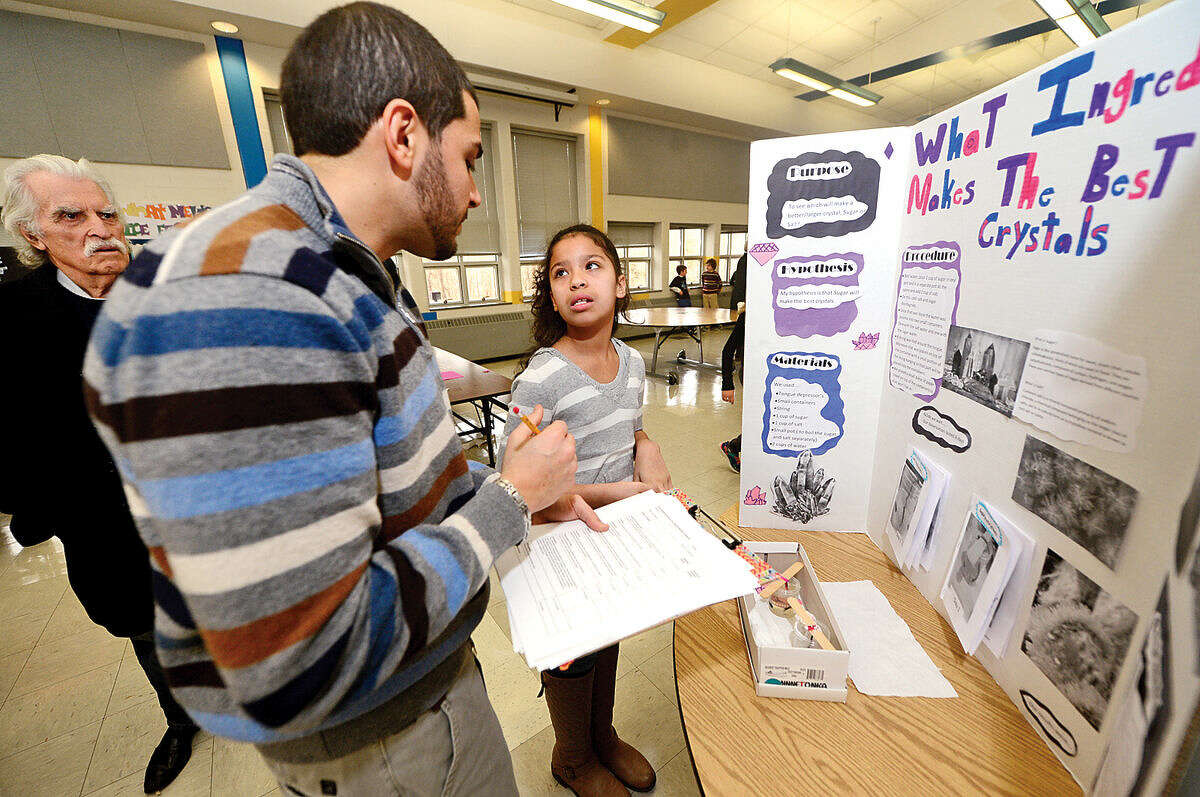 Hour photo / Erik Trautmann Fox Run Elementary School 5th grade teacher, Brian Irrera, judges 5th grader Janelle Ruiz's science project experiment, "What Ingedients Make the Best Crystals", during the school's annual school Science Fair Friday.