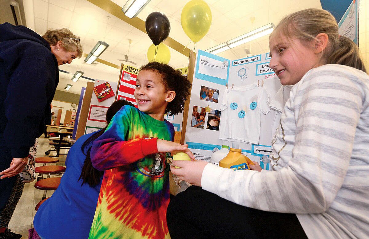 Hour photo / Erik Trautmann Fox Run Elementary School 5th grader Dina Efkarbidis explains her science project, "Store Bought Laundry Detergent Vs Homemade", to first grader Keira Bramble during the school's annual school Science Fair Friday.