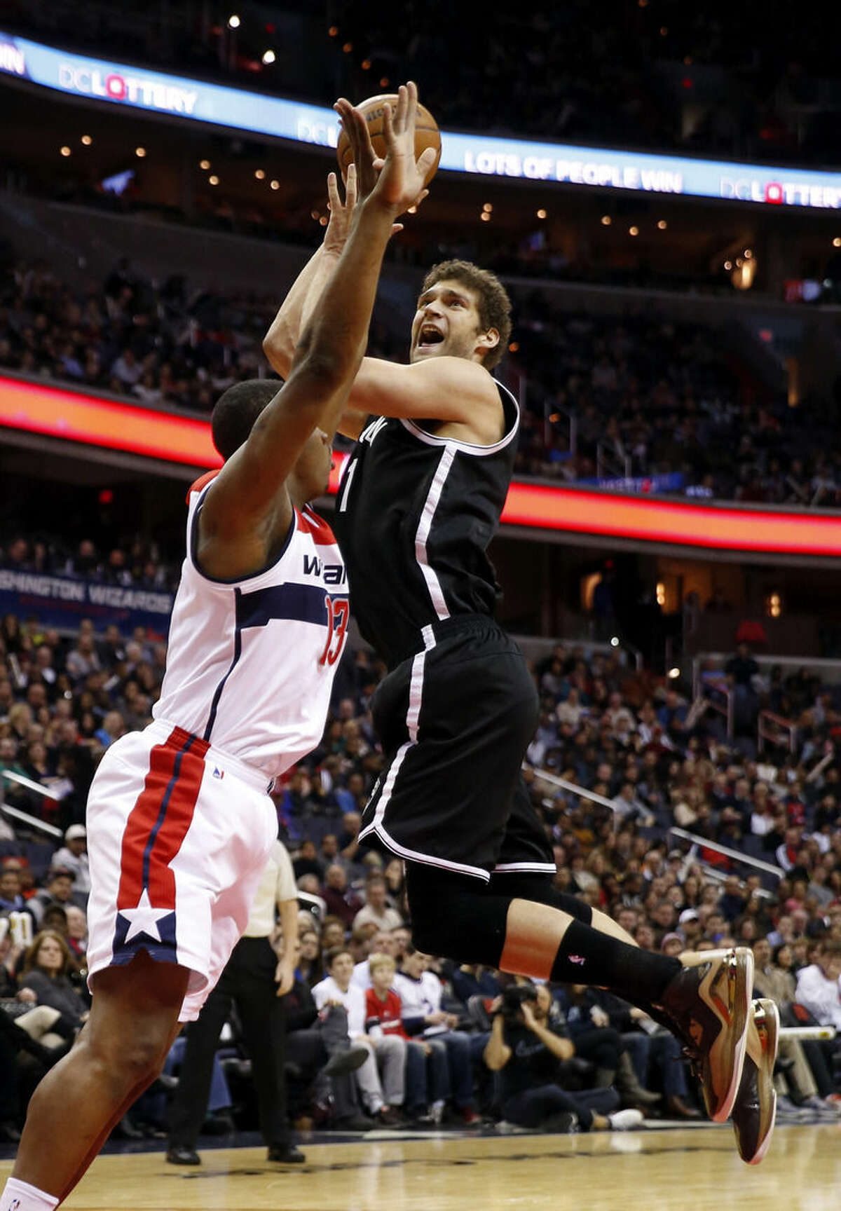 Brooklyn Nets center Brook Lopez (11) tries to shoot over Washington Wizards center Kevin Seraphin (13), from France, in the first half of an NBA basketball game Saturday, Feb. 7, 2015, in Washington. (AP Photo/Alex Brandon)