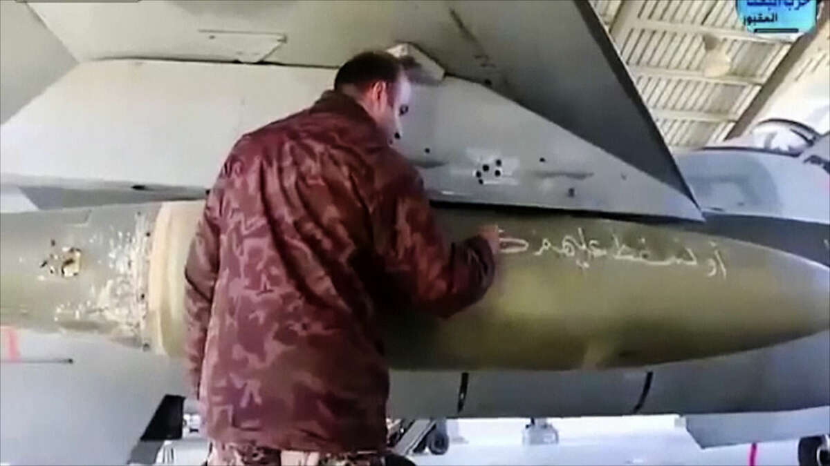 In this image made from Wednesday, Feb. 4, 2015, video provided by Jordanian military via Roya TV, an air force pilot writes a message to Islamic State militants on a missile at Mowafak Al-Salti airbase in Azraq, Jordan. The military carried out airstrikes on Islamic State weapons depots and training sites on Thursday and Friday. King Abdullah II has thrust Jordan to the center of the war against the Islamic State group with his pledge of relentless retaliation for the killing of one of his pilots. (AP Photo/Jordanian military via Roya TV)