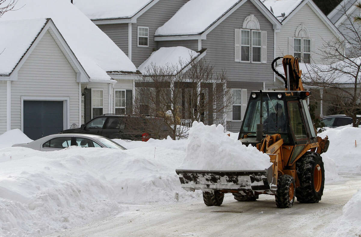 A worker uses a front-end loader to remove piled snow Saturday, Feb. 7, 2015, from a street in Marlborough, Mass. A long duration winter storm was forecast to begin Saturday night and remain in effect for a large swath of southern New England until the early morning hours Tuesday. (AP Photo/Bill Sikes)