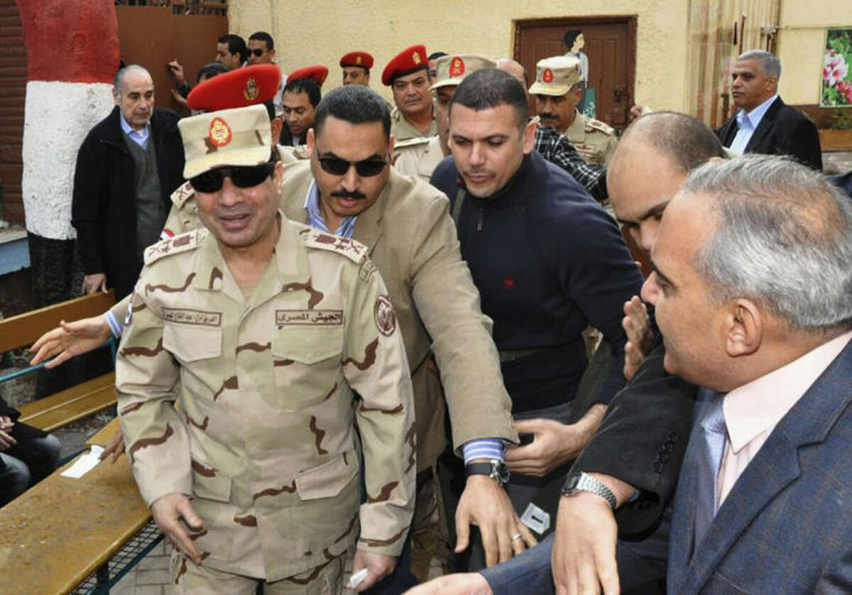FILE - In this Tuesday, Jan. 14, 2014 file photo released by the Egyptian Defense Ministry, Defense Minister Gen. Abdel-Fattah el-Sissi, left, visits a polling site in the Heliopolis neighborhood of Cairo, Egypt, on the first day of voting in the constitutional referendum. Egypt?’s state TV said Monday, Jan. 27, 2014 that the country?’s Interim President issued a presidential decision, promoting the powerful army chief who led the July coup removed Islamist president from power, to the top military rank of marshal. (AP Photo/Egyptian Defense Ministry via Facebook, File)