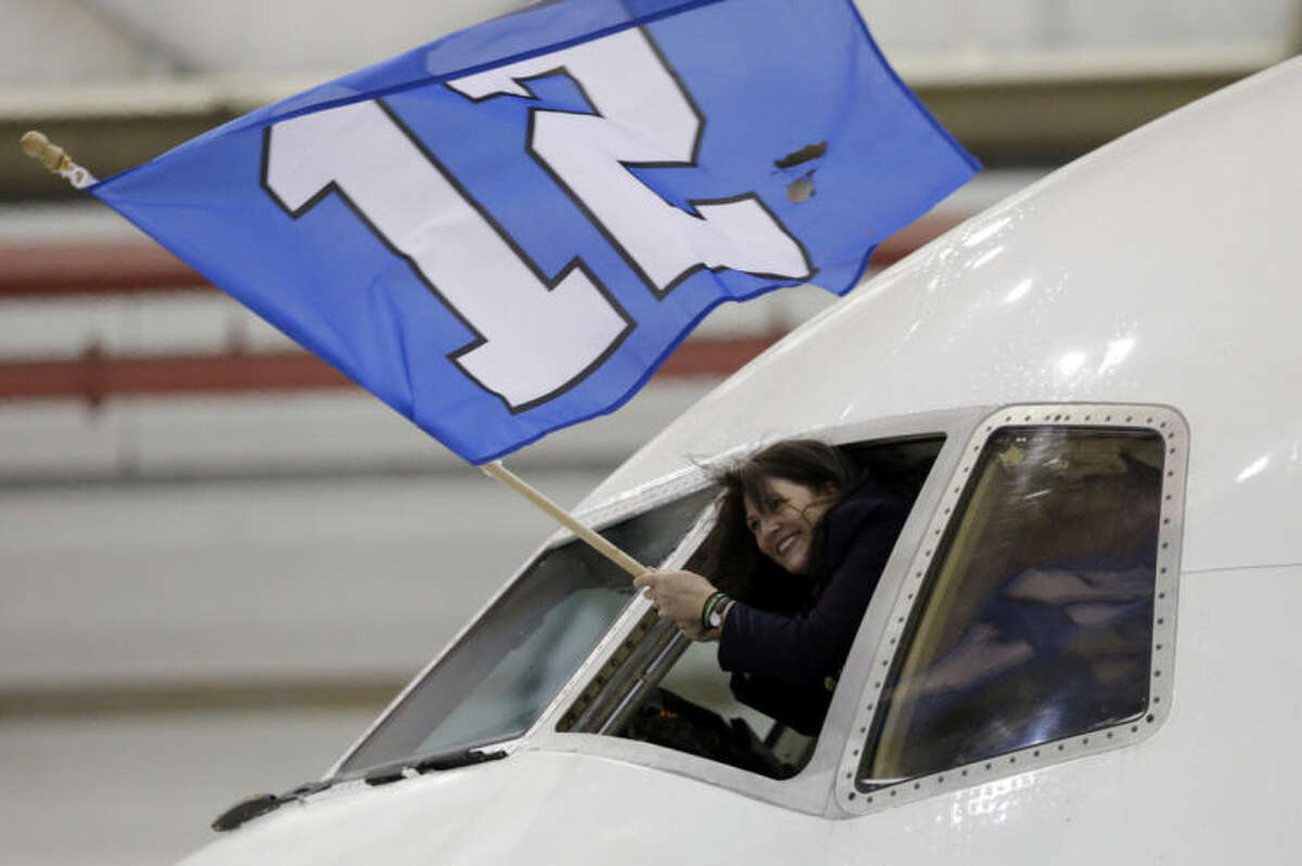 Delta flight attendant Christi Turner waves a flag as the charter plane carrying the Seattle Seahawks arrives at Newark Liberty International Airport for the NFL Super Bowl XLVIII football game, Sunday, Jan. 26, 2014, in Newark, N.J. (AP Photo/Julio Cortez)