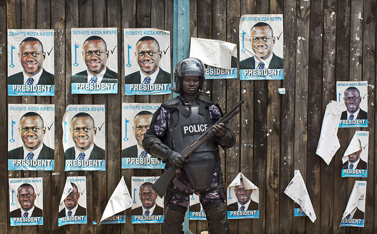 A Ugandan riot policeman blocks the gate of the party headquarters of opposition leader Kizza Besigye, shortly after raiding the premises for the second time in a week, in the capital Kampala, Uganda, Monday, Feb. 22, 2016. Party officials told a group of visiting European Union observers that the security officials had raided the office and arrested eight party staff, just hours before the EU observers had been scheduled to meet with party officials at the building. (AP Photo/Ben Curtis)