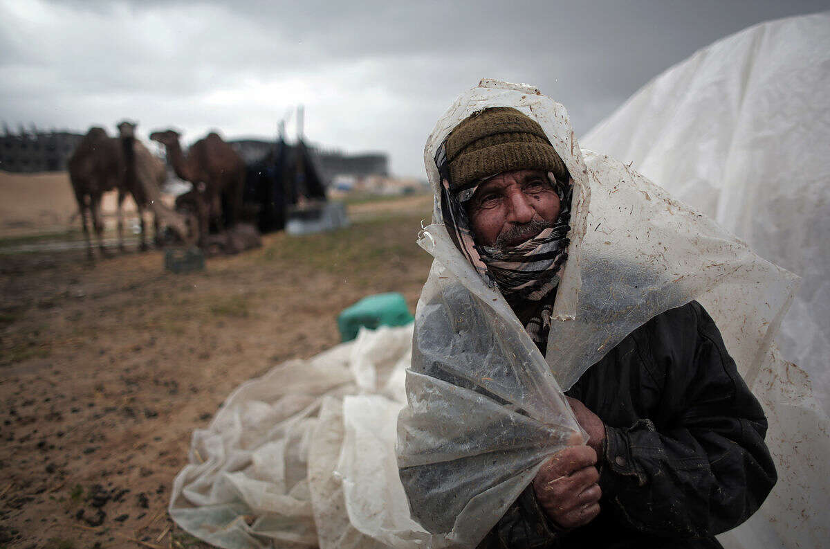 A Palestinian Bedouin man covers his head from the rain in the town of Khan Younis, southern Gaza Strip, Monday, Feb. 22, 2016. (AP Photo/ Khalil Hamra)