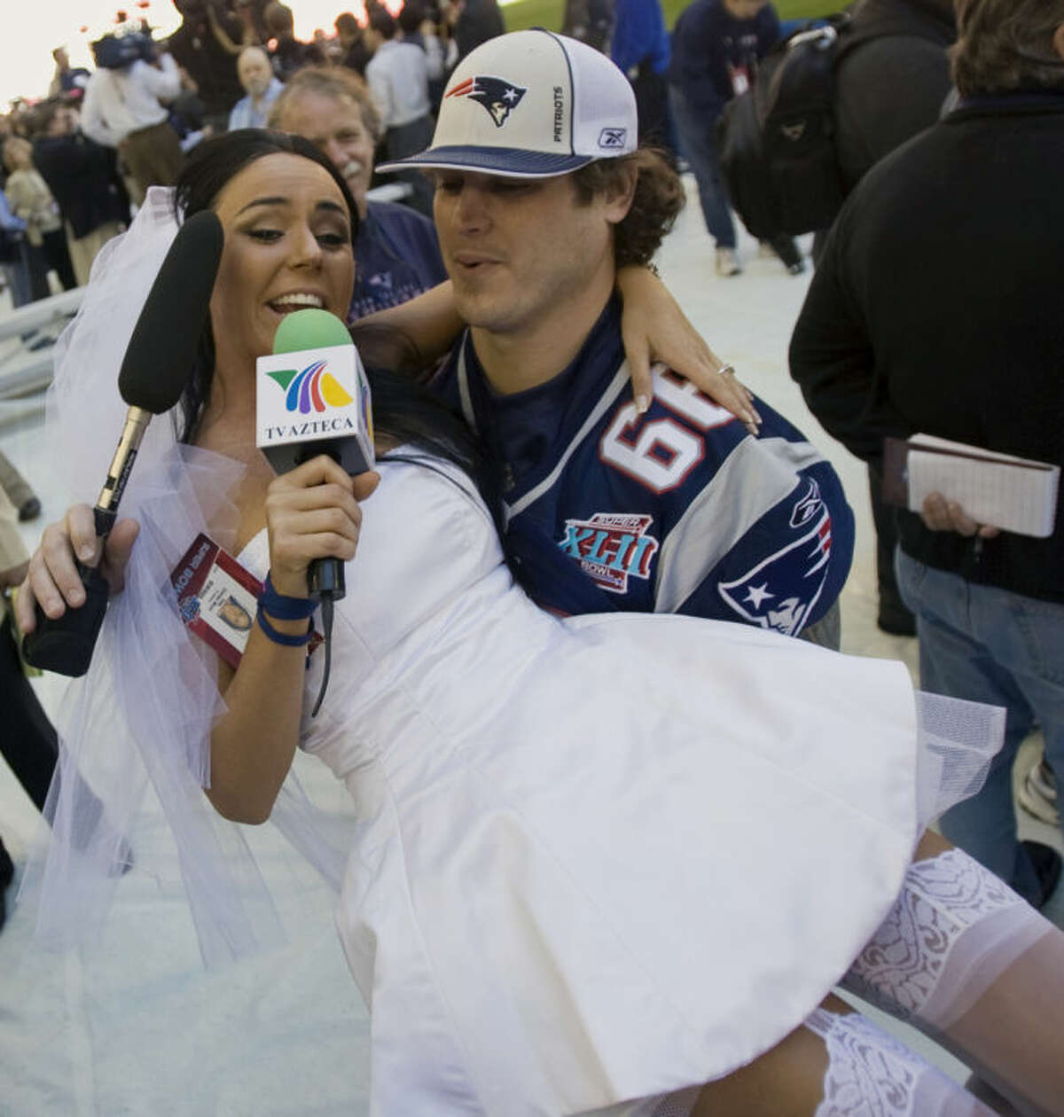 File-This Jan. 29, 2008 file photo shows Ines Gomez Mont, a reporter from TV Azteca in Mexico, wearing a wedding dress as she is carried by New England Patriots center Lonie Paxton while interviewing him during media day for the Super Bowl XLII football game in Glendale, Ariz. Once a serious endeavor, media day is now a forum for credentialed "media" such as Mont. The entertainment reporter for Mexico's TV Azteca showed up in Glendale, Ariz., wearing a scanty white wedding dress and towering red pumps. She spent the next two hours trying to persuade someone, anyone, to accept her marriage proposal. (AP Photo/The Arizona Republic, Michael Chow, File)