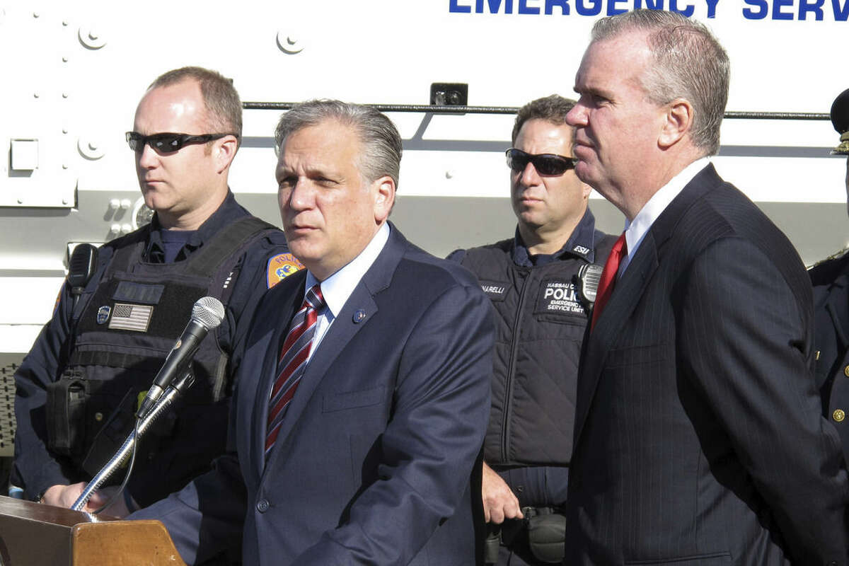 FILE- In this Nov. 16, 2015 file photo, Nassau County Executive Edward Mangano, second left, and Nassau County's acting Police Commissioner Thomas Krumpter, right, speak at a news conference in Mineola, N.Y. Mangano says he is a victim of cybercrime and is vehemently denying allegations in a TV report that he sent sexually suggestive texts to a public relations executive who has done work for the county. (AP Photo/Frank Eltman, File)