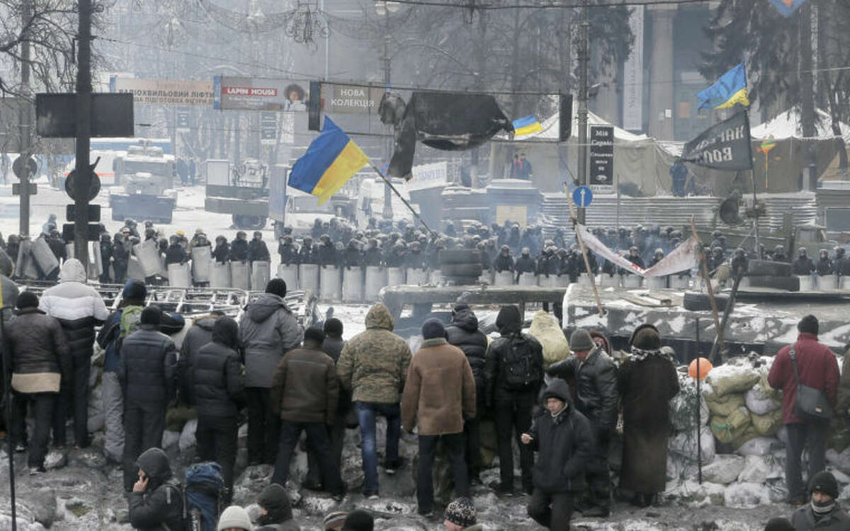 Protesters guard the barricades in front of riot police in Kiev, Ukraine, Wednesday, Jan. 29, 2014. Ukraine's parliament is considering measures to grant amnesty to those arrested during weeks of protests in the crisis-torn country, but possibly with conditions attached that would be unacceptable to the opposition. (AP Photo/Efrem Lukatsky)