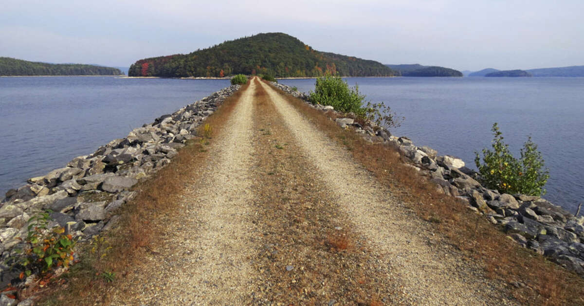 FILE-- In this September 2013 handout file photograph from the Mass. Dept. of Conservation and Recreation, a dirt and stone road leads to Mount Zion Island, at rear, at the Quabbin Reservoir in Petersham, Massachusetts. A plan by the state to start a colony of venomous timber rattlesnakes on the off-limits island in Massachusetts’ largest drinking water supply is under fire. (Clif Read/The Mass. Dept. of Conservation and Recreation via AP)