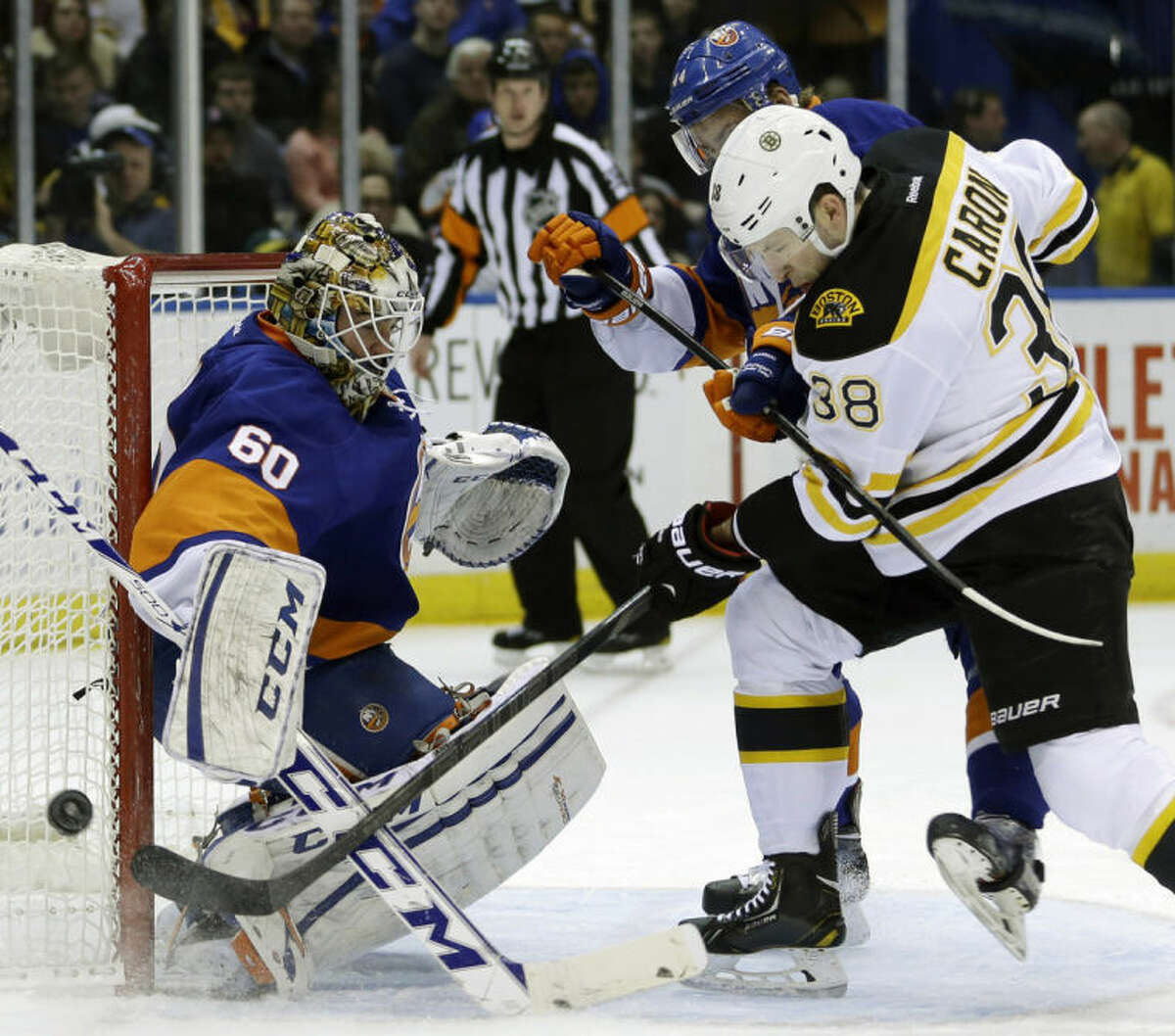 Boston Bruins' Jordan Caron, right, and New York Islanders' Calvin de Haan scuffle for the puck in front of goalie Kevin Poulin, left, during the first period of the NHL hockey game, Monday, Jan. 27, 2014, in Uniondale, New York. (AP Photo/Seth Wenig)