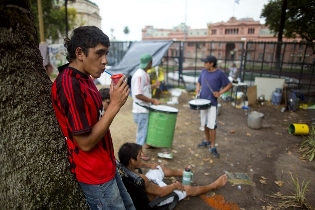 Unemployed youth who belong to a nationwide organization of unemployed and retired people camp outside the Casa Rosada government palace, background, to protest government policies that they believe exclude the poor in Buenos Aires, Argentina, Tuesday, Jan. 28, 2014. Argentina is suffering one of the world's highest inflation rates. (AP Photo/Victor R. Caivano)