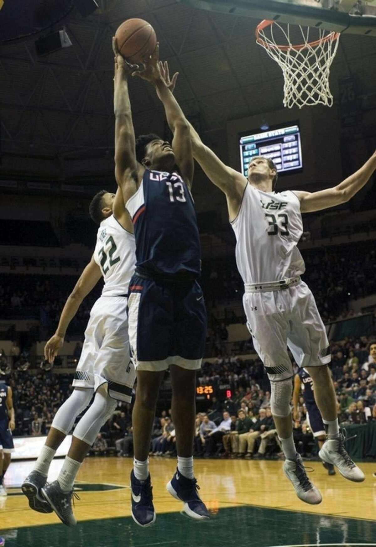Connecticut's Steven Enoch (13) pulls in a rebound between South Florida's Angel Nunez (22) and Ruben Guerrero (33) during the first half of an NCAA college basketball game Thursday, Feb. 25, 2016 in Tampa, Fla. (AP Photo/Steve Nesius)
