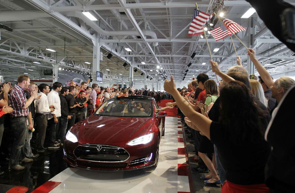 FILE - In this June 22, 2012 file photo, Tesla workers cheer on the first Tesla Model S cars sold during a rally at the Tesla factory in Fremont.