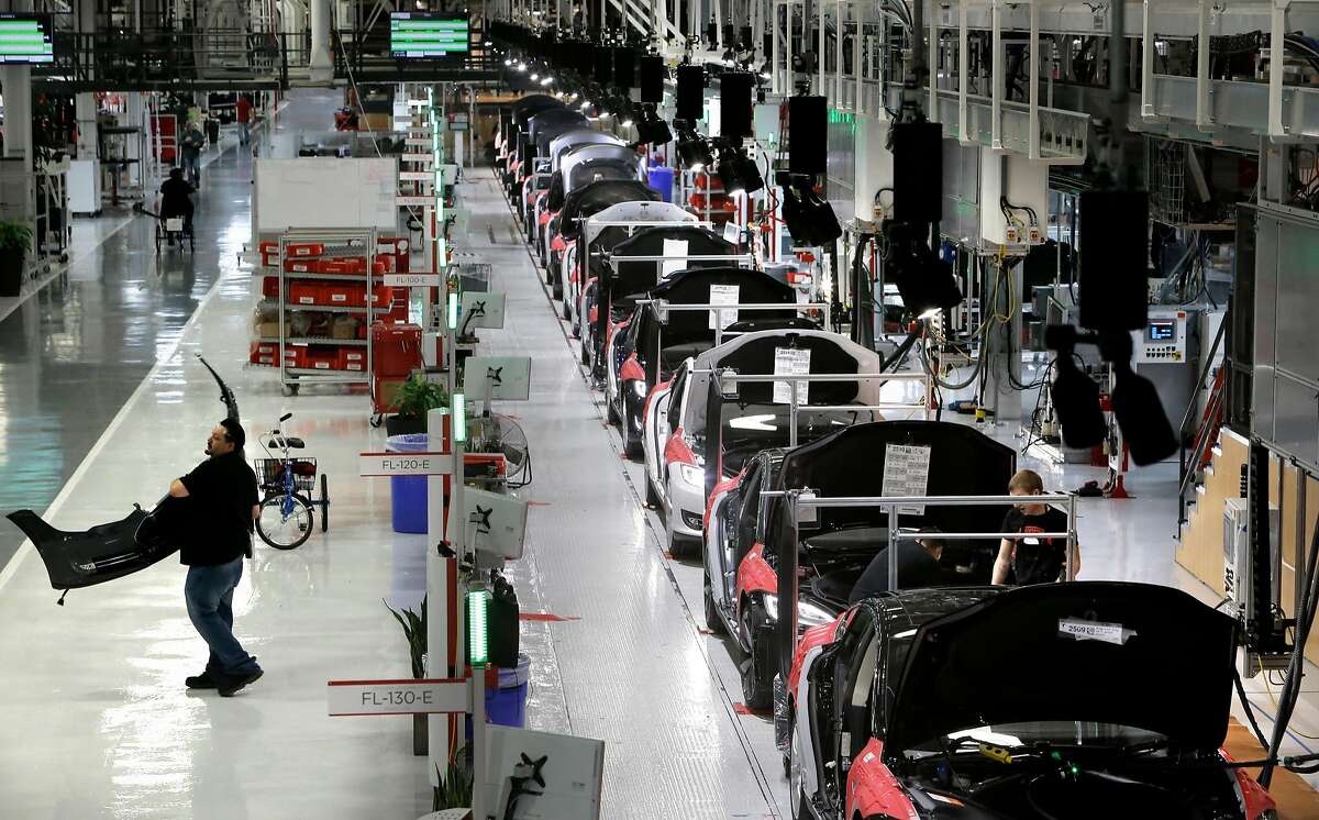 A worker carries a front end part along the assembly at Tesla Motors, California's only full-scale auto manufacturing plant, as seen on Thurs. Feb. 19, 2015, in Fremont.