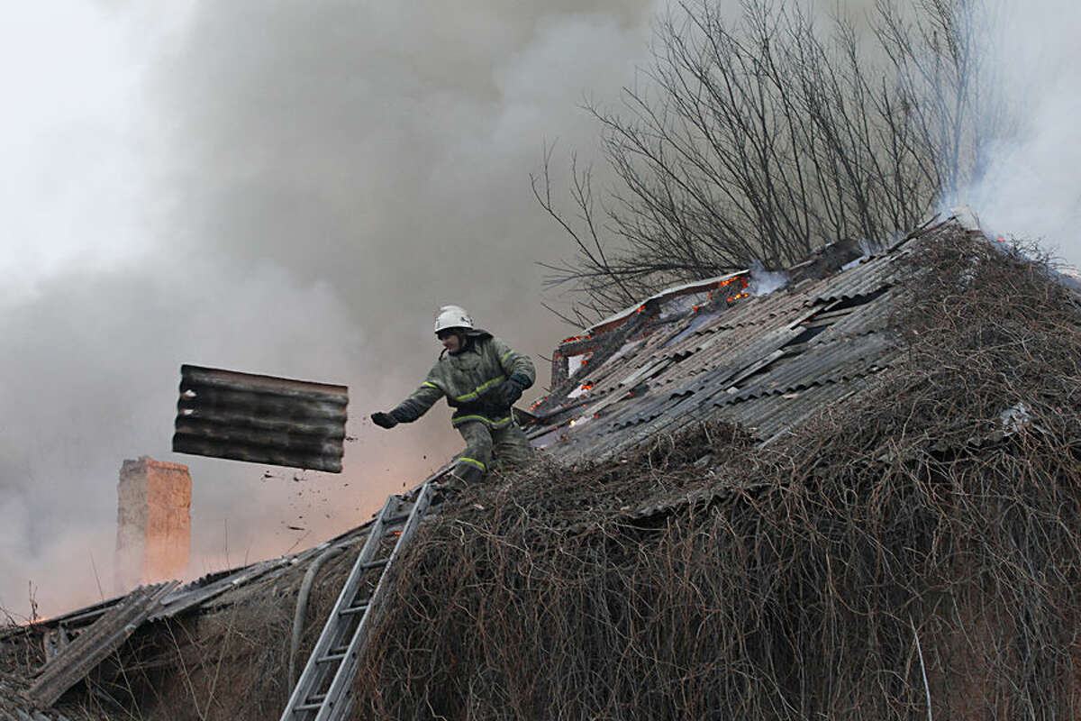 A firefighter dismantles a roof to extinguish a building on fire after shelling between Russian-backed separatists and Ukrainian government in residential area of the town of Artemivsk, Ukraine, Saturday, Feb. 14, 2015. Despite a looming cease-fire deal for eastern Ukraine, a government-held town 40 kilometers (25 miles) behind the front line has been hit by shelling. The deadline for the warring sides to halt hostilities is Sunday morning at one minute after midnight. (AP Photo/Petr David Josek)