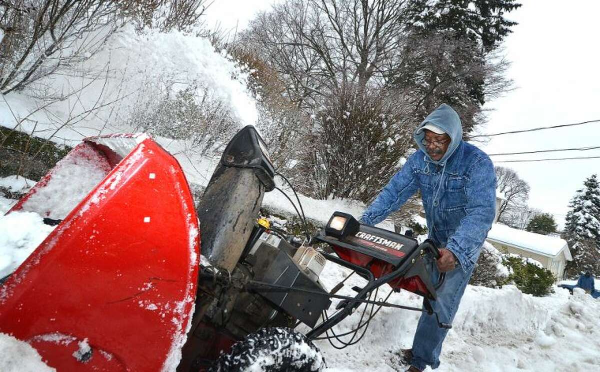 Hour Photo/Alex von Kleydorff. John Ruffin pushes his snowblower trough the heavy snow to clear the sidewalk for pedetstrians in front of his Norwalk home on Wednesday