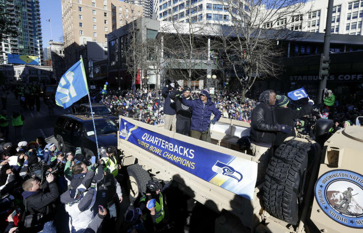 Seattle Seahawks quarterback Russell Wilson, center, waves to fans during the Super Bowl champions parade on Wednesday, Feb. 5, 2014, in Seattle. The Seahawks defeated the Denver Broncos 43-8 in NFL football's Super Bowl XLVIII on Sunday. (AP Photo/Ted S. Warren)