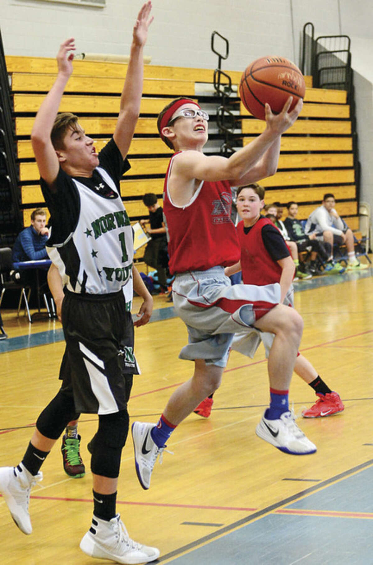 Hour photo / Erik Trautmann Austin Hall of TMT, right, puts up a shot as Peter Meyerson of Norwalk Youth defends during the seventh grade championship game of the Fairfield County Basketball League on Saturday at Ridgefield High. TMT defeated Youth 55-46 to claim the title.