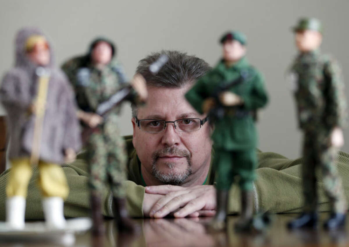 In this Jan. 31, 2014 photo Tearle Ashby poses with some of his G.I. Joe action figures in Niskayuna, N.Y. A half-century after the 12-inch doll was introduced at a New York City toy fair, the iconic action figure is being celebrated by collectors with a display at the New York State Military Museum, while the toy's maker plans other anniversary events to be announced later this month. (AP Photo/Mike Groll)