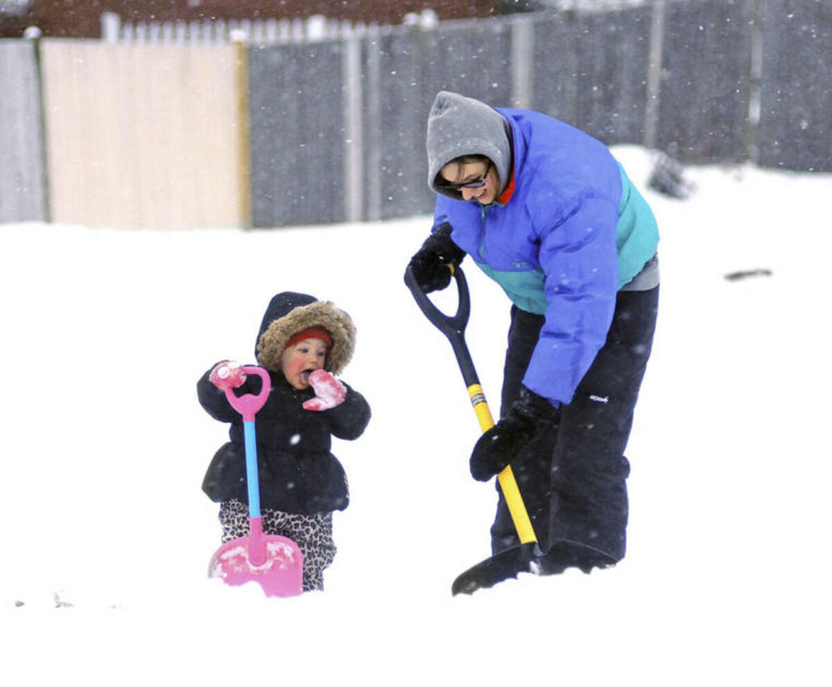 While Lauren Berthiaume, right, shovels her sidewalk, her 17-month-old daughter Rylie Bartusek prefers eating the snow, Wednesday, Feb. 5, 2014, in Worcester, Mass. (AP Photo/Worcester Telegram & Gazette, Steve Lanava)