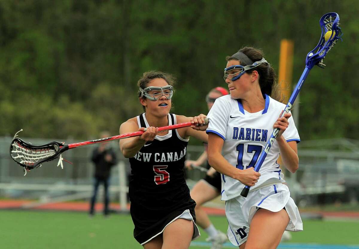 New Canaan Karlie Bucci checks Darien Chandler Kirby as she drive the middle in a FCIAC girls lacrosse game at Darien High School on May 10, 2016. Darien defeated New Canaan 20-10.