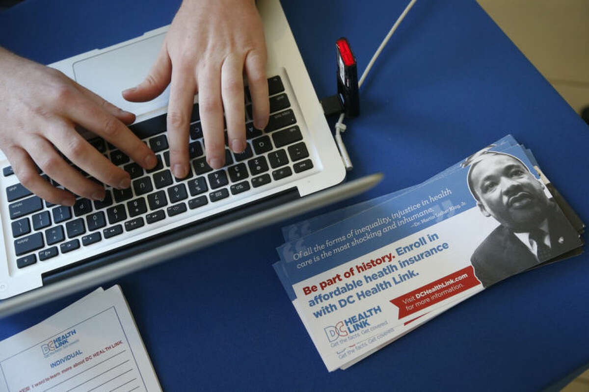 David Bransfield, a state outreach coordinator for Young Invincibles, a group which supports President Barack Obama's health care law, works on his computer at a table set up to sign people up for health care at the University of the District of Columbia in Washington, Thursday, Jan. 30, 2014. An army of workers and volunteers has fanned out around the country trying to enroll young and healthy people in health insurance now available through Obama?’s signature law. (AP Photo/Charles Dharapak)