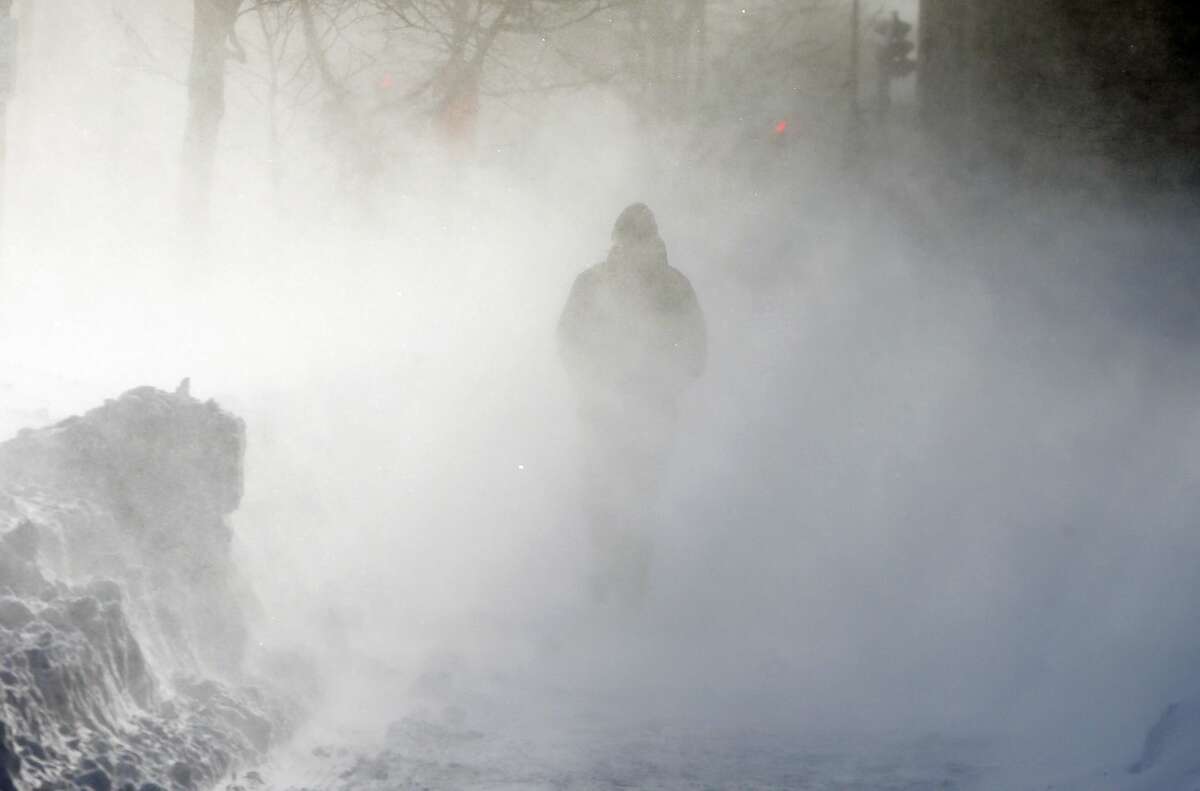 A pedestrian walks through drifting snow driven by strong wind in Boston, Sunday, Feb. 15, 2015. A storm brought a new round of wind-whipped snow to New England on Sunday, threatening white-out conditions in coastal areas and forcing people to contend with a fourth winter onslaught in less than a month. (AP Photo/Michael Dwyer)