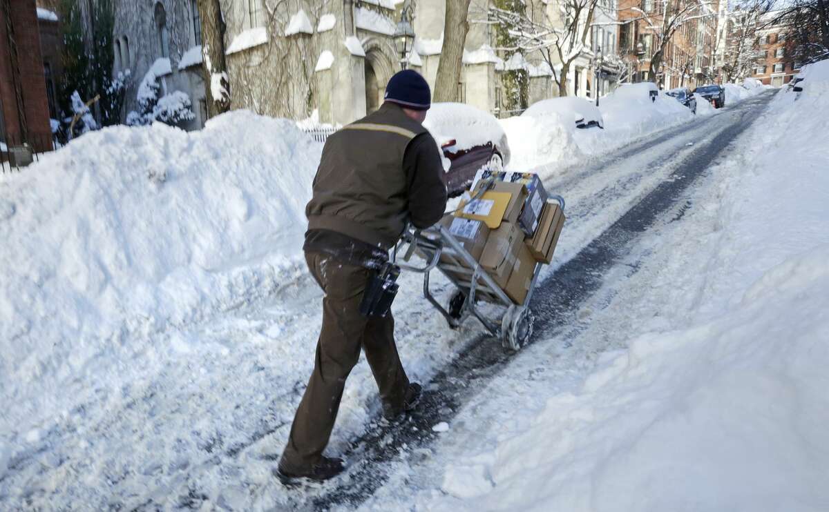 Joe Riley, of Braintree, Mass., pushes a hand cart up Beacon Hill while making deliveries in Boston, Tuesday, Feb. 3, 2015. Riley, a United Parcel Service driver, decided to make most of his deliveries on foot due to the 40 inches of snow the area has received this past week, causing gridlock in much of the city. (AP Photo/Charles Krupa)
