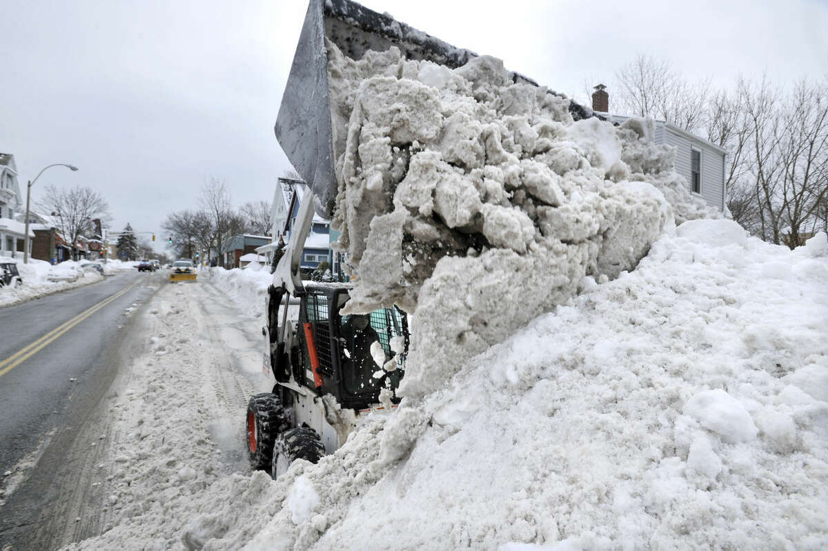 A worker uses a compact front-end loader to pile snow from a road to be removed by a dump truck near Davis Square in Somerville, Mass., Tuesday, Feb. 10, 2015. The third major winter storm in two weeks left the Boston area with another two feet of snow and forced the MBTA to suspend all rail service for the day. (AP Photo/Josh Reynolds)