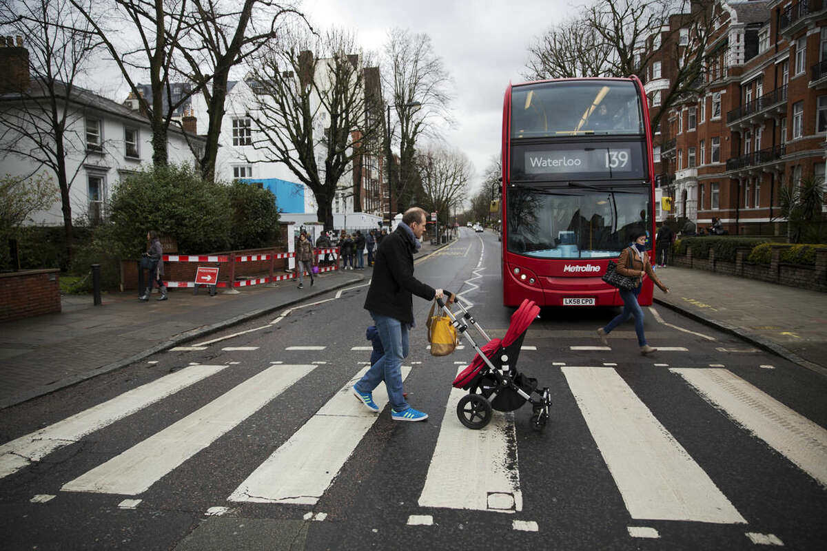People walk over the zebra crossing where the cover picture of the Beatles' Abbey Road album was taken outside Abbey Road studios in London, Wednesday, March 9, 2016. George Martin, the Beatles' urbane producer who quietly guided the band's swift, historic transformation from rowdy club act to musical and cultural revolutionaries, has died, his management said Wednesday. He was 90. (AP Photo/Matt Dunham)