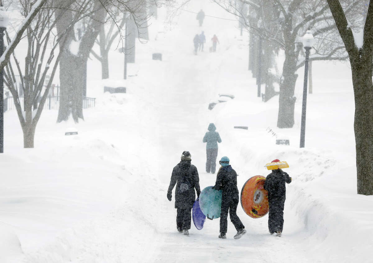 People carry their sleds at the Boston Common, Monday, Feb. 9, 2015, in Boston. The third major winter storm in less than two weeks inflicted fresh snow across New England and portions of New York state on Monday. (AP Photo/Steven Senne)