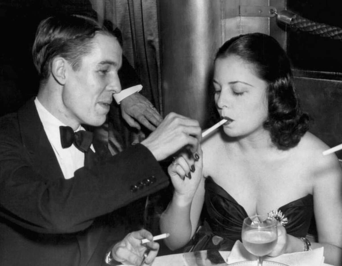 FILE - In this Oct. 16, 1937 file photo, Alfred Gwynne Vanderbilt lights the cigarette of Eleanor Young at the opening of the Sert Room of the Waldorf Astoria in New York. (AP Photo)