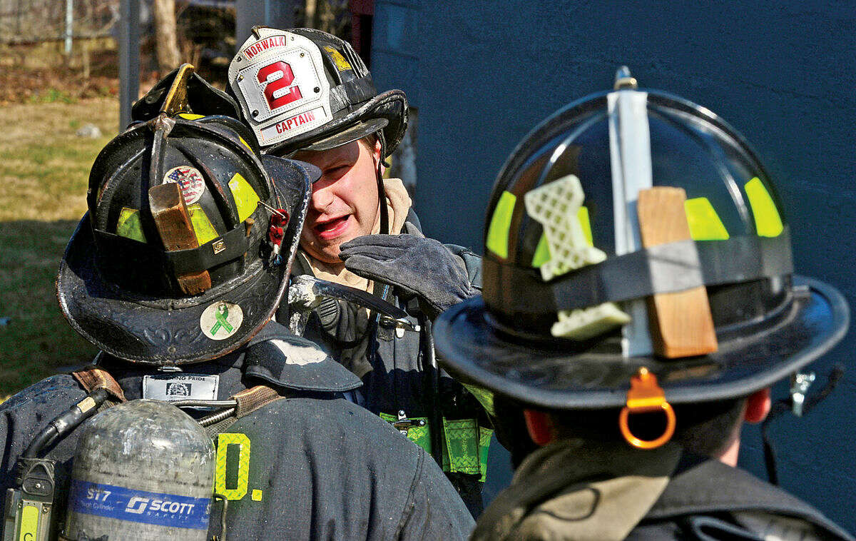 Hour photo / Erik Trautmann Norwalk firefighters battle a fire that engulfed the rear deck of the home at 25 Leuvine Street in Norwalk Tuesday afternoon.