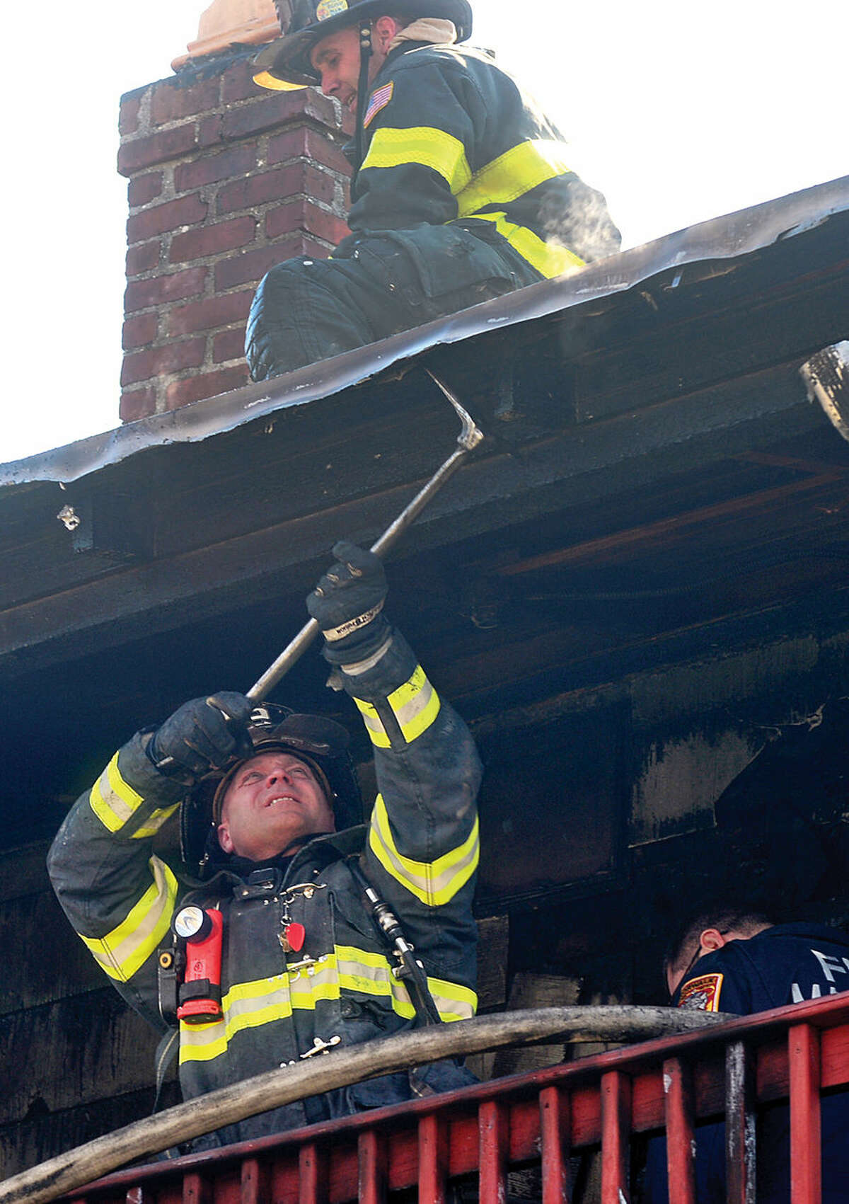 Hour photo / Erik Trautmann Norwalk firefighters battle a fire that engulfed the rear deck of the home at 25 Leuvine Street in Norwalk Tuesday afternoon.