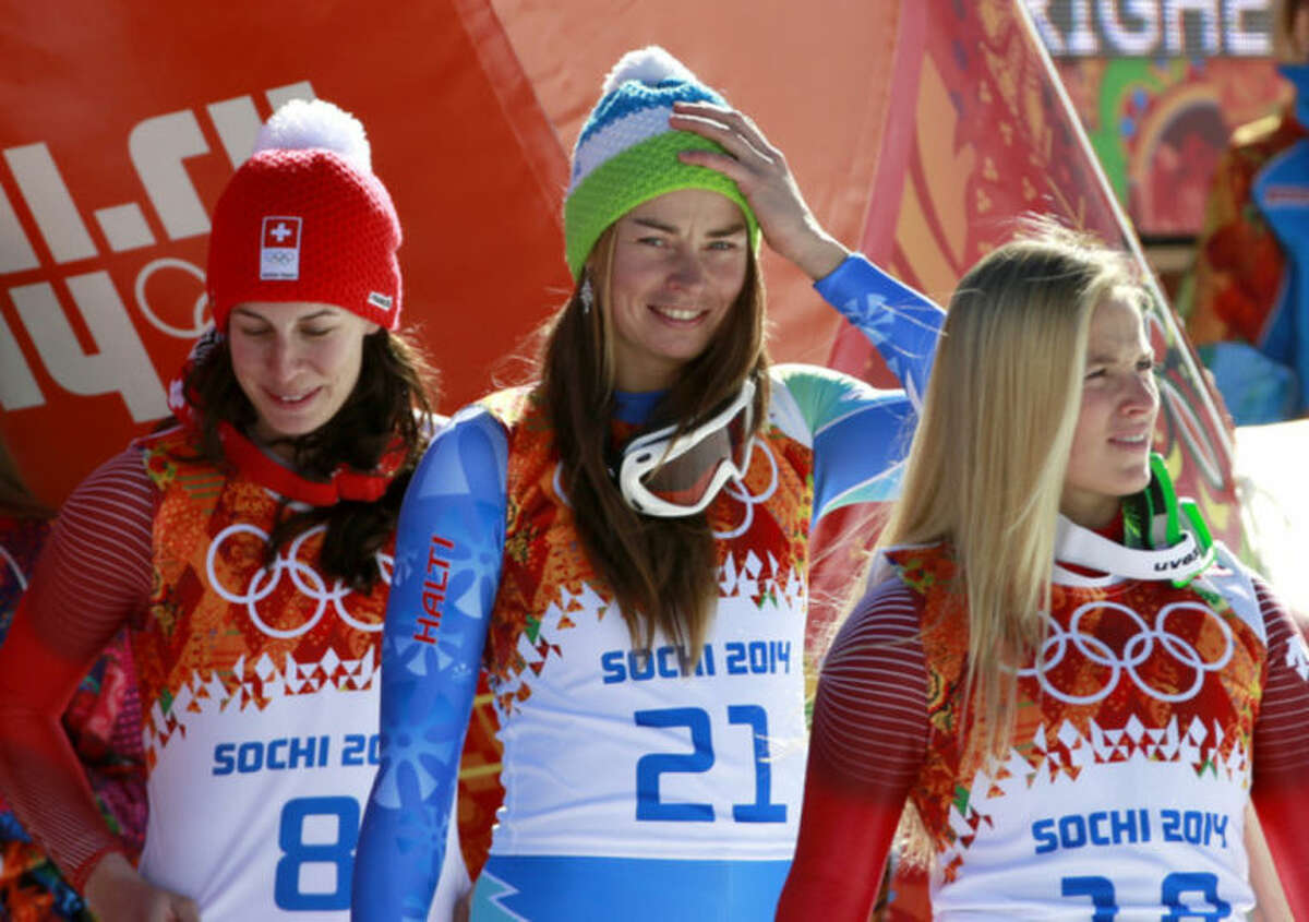Women's downhill gold medalists Switzerland's Dominique Gisin, left, and Slovenia's Tina Maze, center, stand with bronze medalist Switzerland's Lara Gut before a flower ceremony at the Sochi 2014 Winter Olympics, Wednesday, Feb. 12, 2014, in Krasnaya Polyana, Russia. (AP Photo/Gero Breloer)
