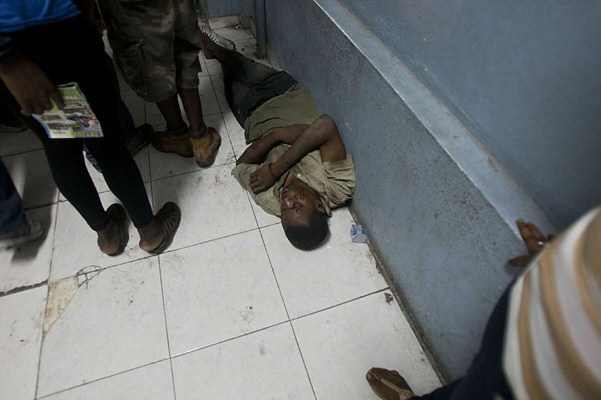 A man waits for treatment on the floor of the emergency room at the General Hospital in Port-au-Prince, Haiti, early Tuesday, Feb. 17, 2015. At least 20 people on a music group's packed Carnival float in the Haitian capital were killed Tuesday when they were electrocuted by a power line, officials said. The accident occurred as thousands of people filled the streets of downtown Port-au-Prince for the raucous annual celebration. People at the scene said someone on the float used a pole or stick to move a power line so the float could pass under it.( AP Photo/Dieu Nalio Chery)
