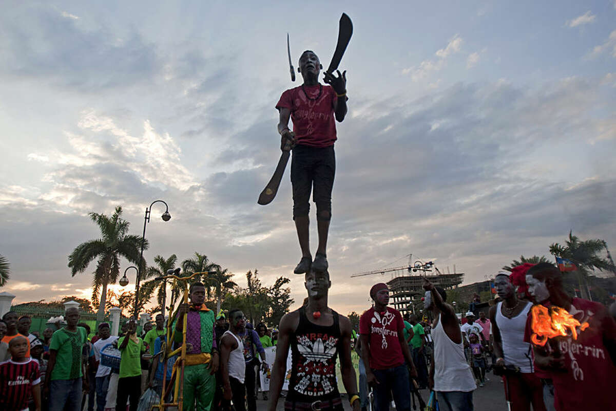 A performer juggles machetes while standing on the top of his partner's head, during Carnival celebrations in Port-au-Prince, Haiti, Monday, Feb. 16, 2015. (AP Photo/Dieu Nalio Chery)