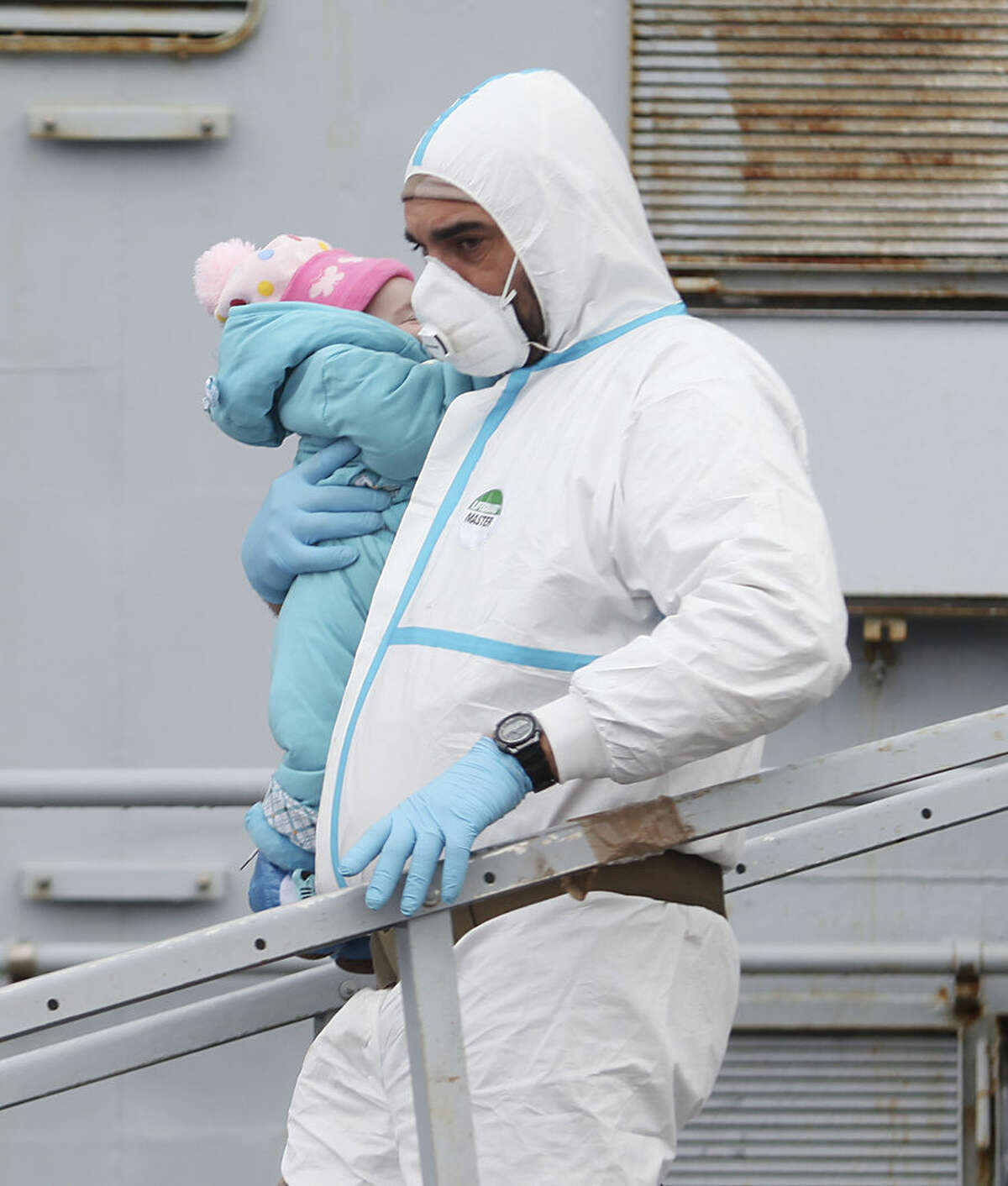 An Italian Navy officer carries a baby as migrants disembark from a tug boat after being rescued in Porto Empedocle, Sicily, southern Italy, Tuesday, Feb. 17, 2015. With Libya's security rapidly deteriorating, the number of migrants who set out in smugglers boats from Libyan shores toward Italy has surged. (AP Photo/Francesco Malavolta)