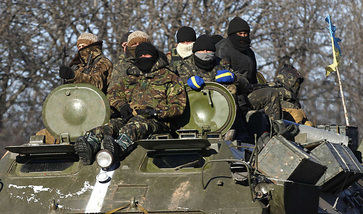 Ukrainian government soldiers sit on top of their armored vehicle driving on a road stretching away from the town of Artemivsk, Ukraine, towards Debaltseve, Tuesday, Feb. 17, 2015. Ukrainian government troops and Russia-backed rebels failed Tuesday to start pulling back heavy weaponry from the front line in eastern Ukraine as a deadline passed to do so. Under a cease-fire agreement negotiated by the leaders of Ukraine, Russia, Germany and France last week, the warring sides were to begin withdrawing heavy weapons from the front line on Tuesday. (AP Photo/Petr David Josek)